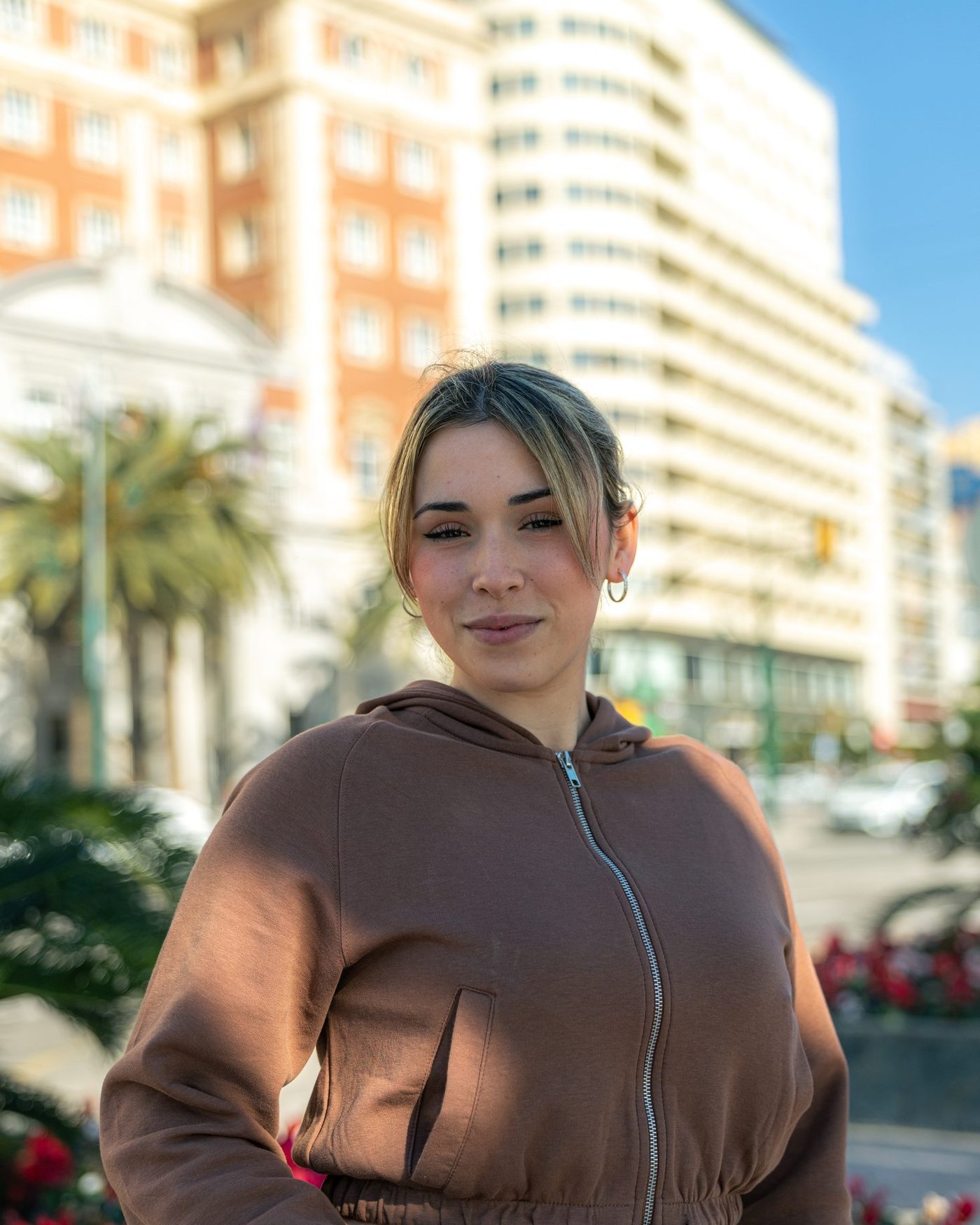 Retrato de mujer con sudadera marrón en una plaza de Málaga